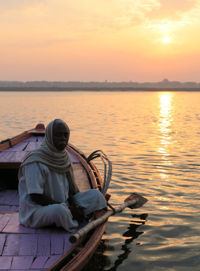 Vieil homme assis dans sa barque au Soleil levant