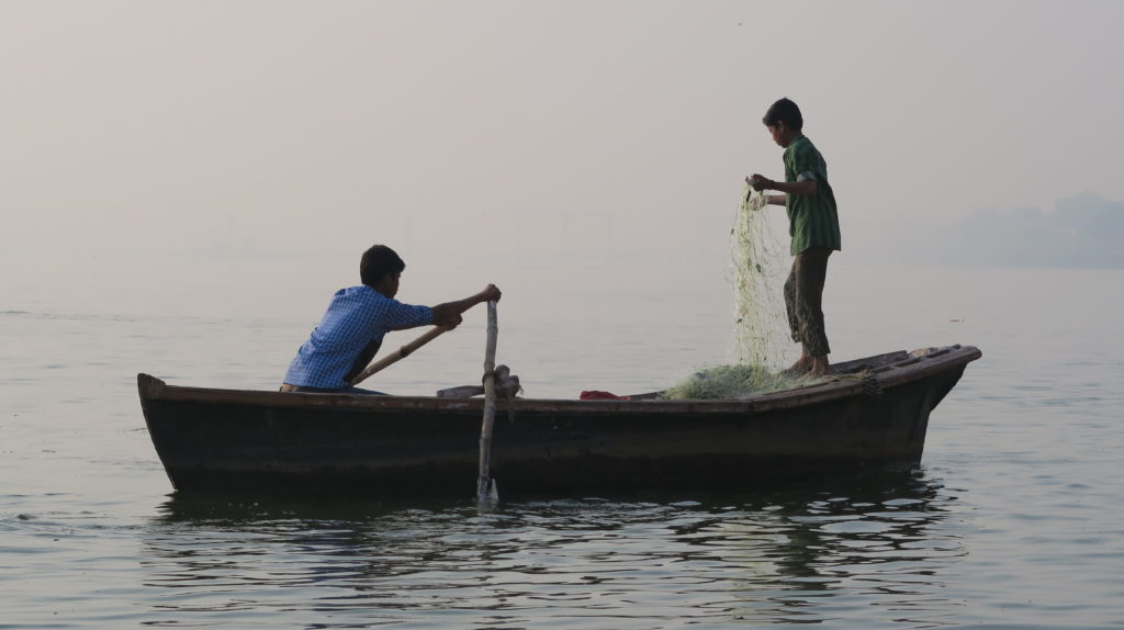 Deux jeunes sont dans un bateau et pêchent au petit matin