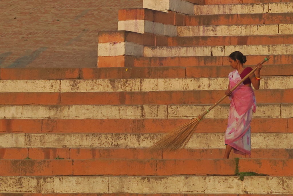 Femme avec balai qui nettoie les marches du ghat