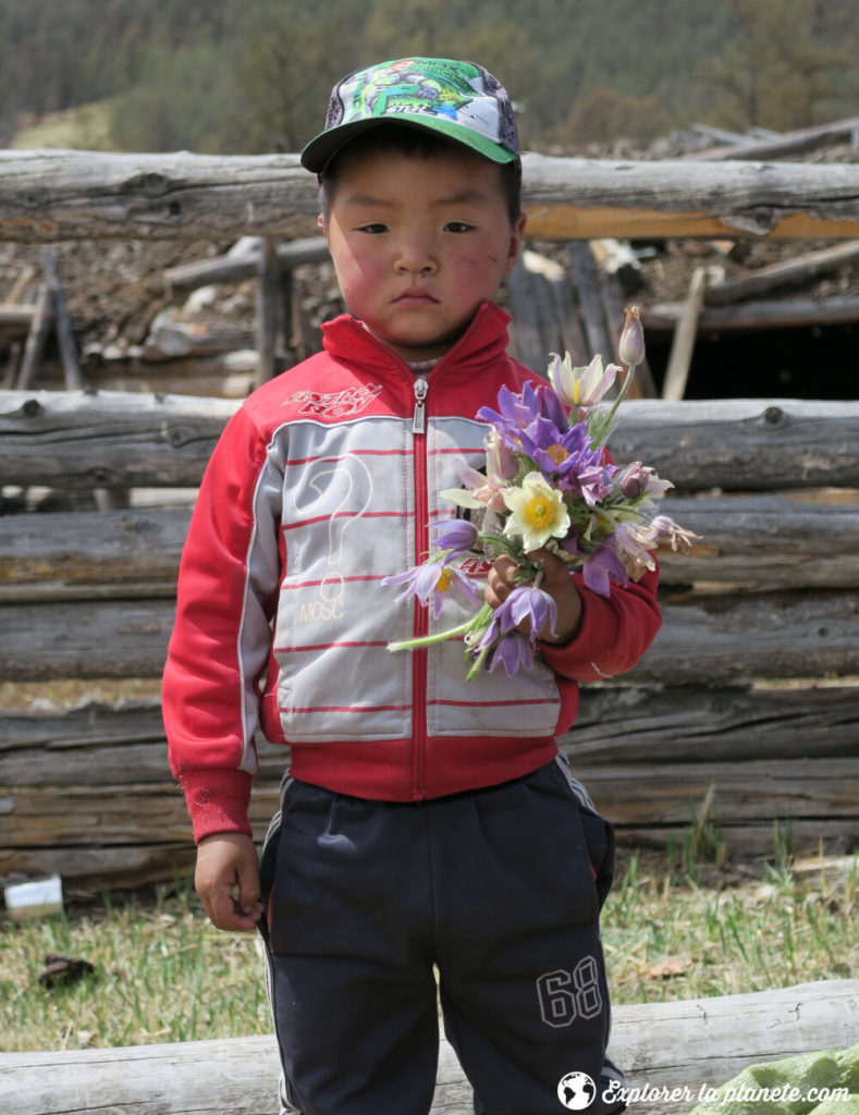 Un jeune garçon mongol avec un bouquet de fleur.