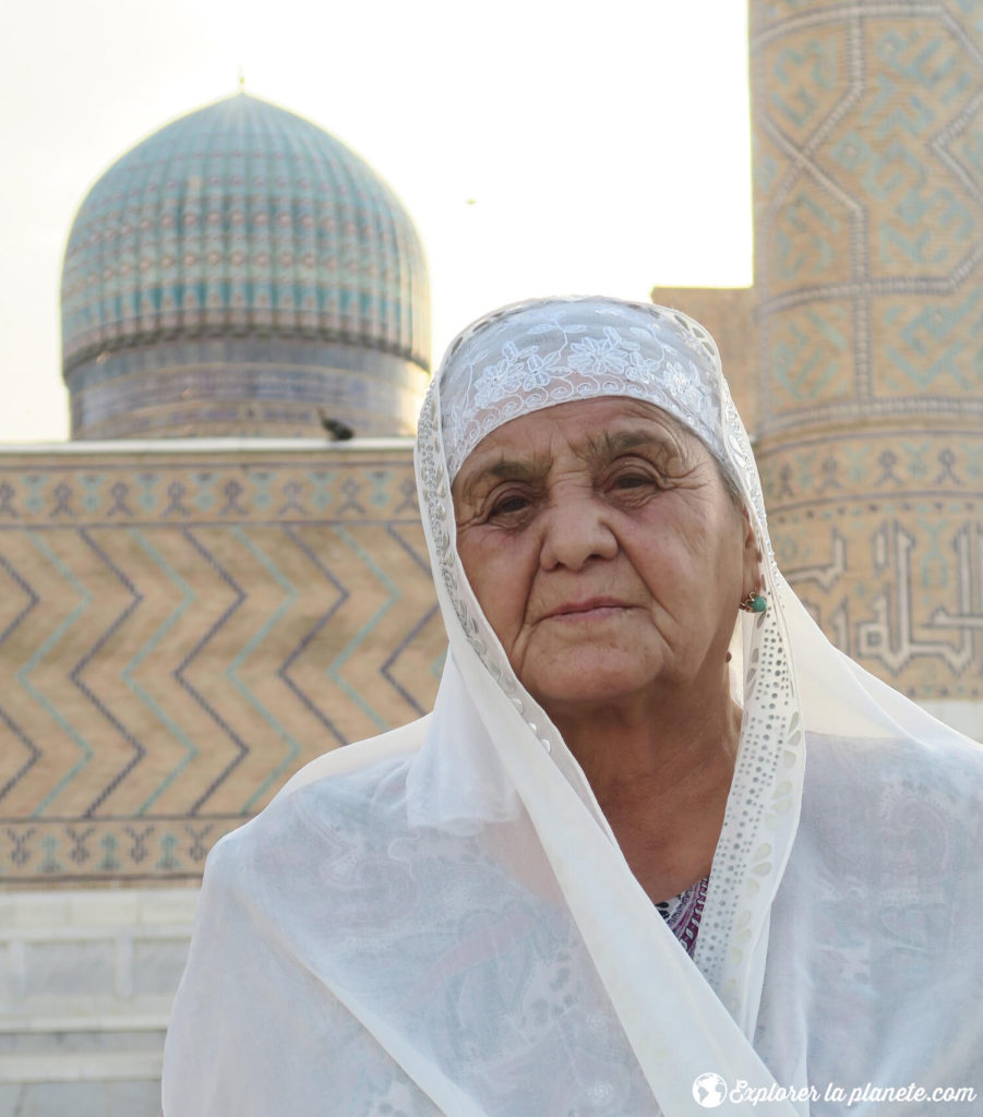 Portrait d'une dame voilée devant le dôme d'une médersa au Régistan de Samarcande.