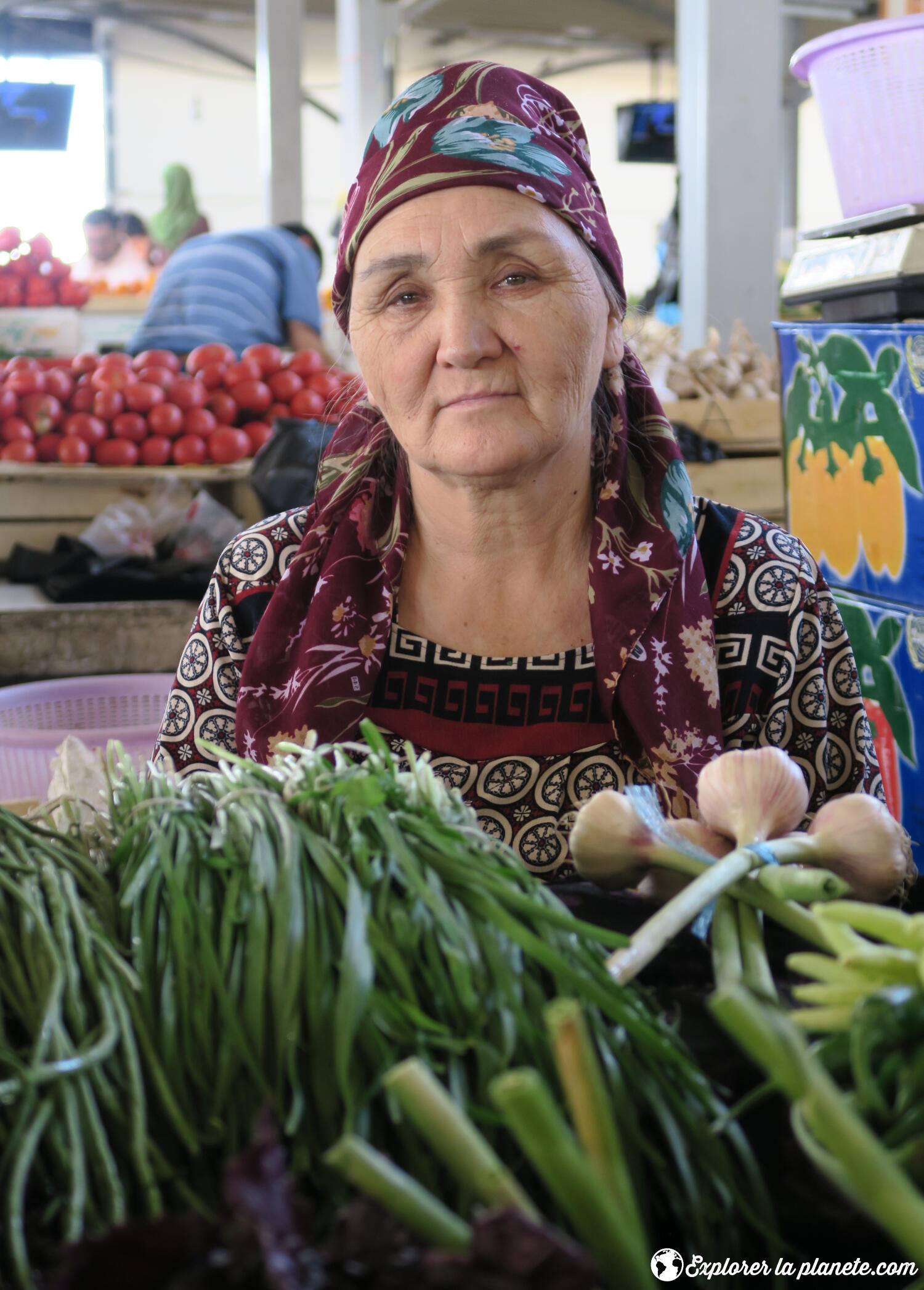 Une dame qui vend des légumes dans un marché.